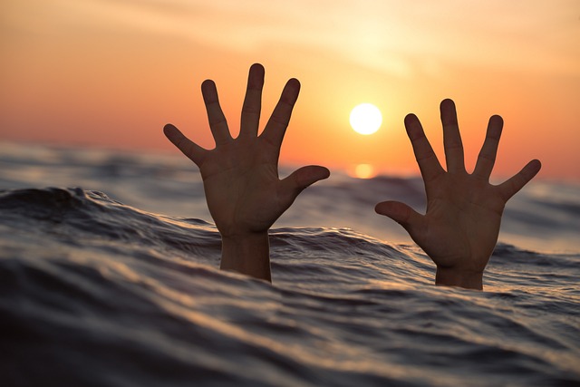 Picture of two hands above water seeking help