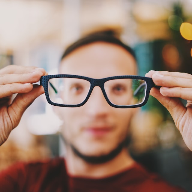 Picture of a person holding a pair of spectacles 