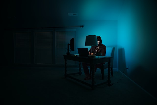 Picture of a masked hacker sitting a computer 