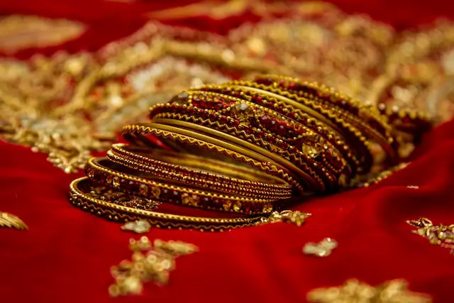 Picture of several gold bangles laying on a red cloth