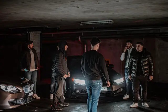 A picture of a gang surrounding a car 