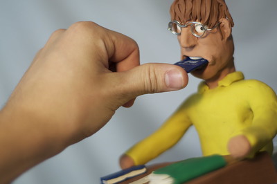 picture of person force feeding a clay figure 