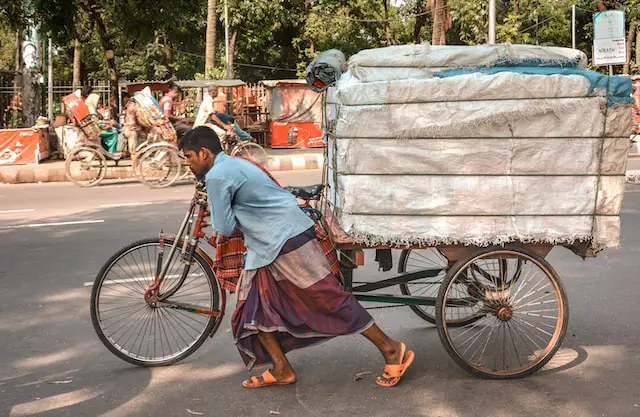 Picture of a man waring a sarong pushing a bicycle 