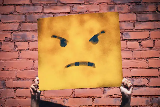 Picture of a person holding an image of an angry face