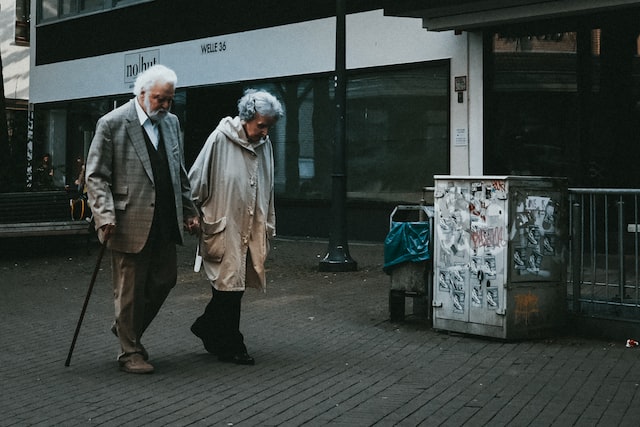 Picture of an elderly couple walking in the street while holding hands