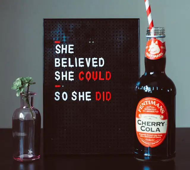 Picture of a cola bottle next to sign that has a positive affirmation printed on it