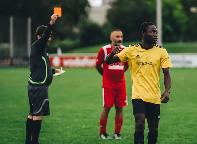 Picture of a football player being shown the red card by a referee 
