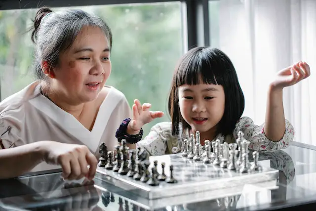 Picture of a nanny playing chess with a child