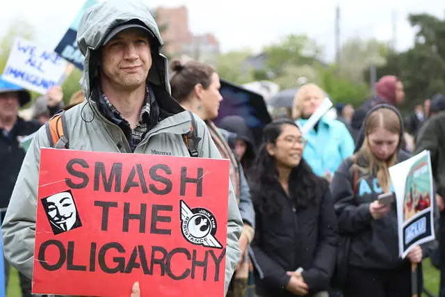 picture of a person holding a placard that says" smash the oligarchy"