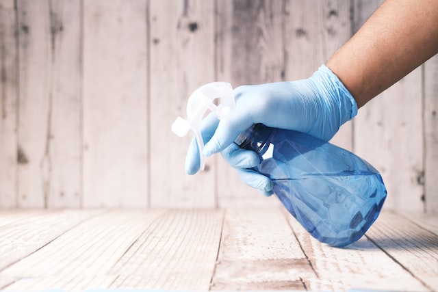 Picture of a person spraying disinfectant on a solid surface