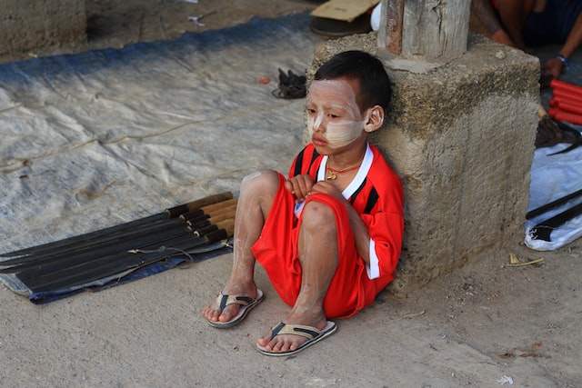 Picture of a small boy sitting on the ground waring sunscreen or sunblock