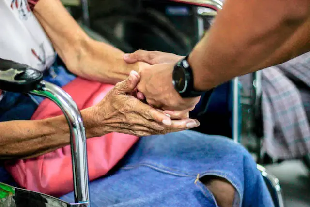 Picture of a person holding the hand of a disabled person 