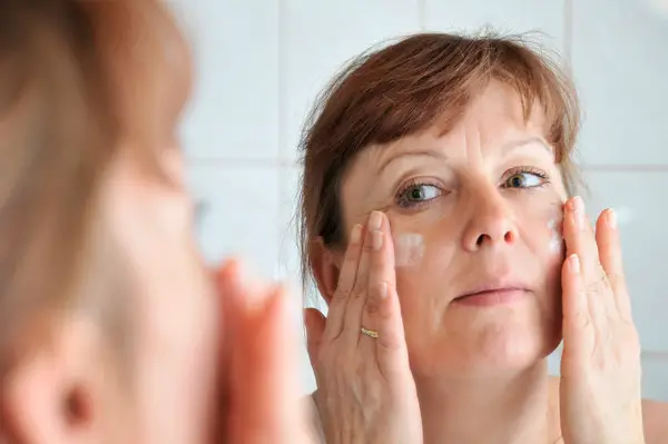 picture of a woman applying cream to her face