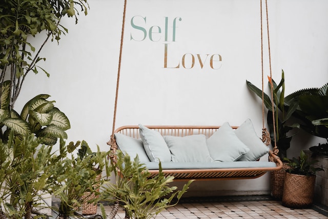 Picture of a cozy chair with "Self Love" printed on the wall behind it