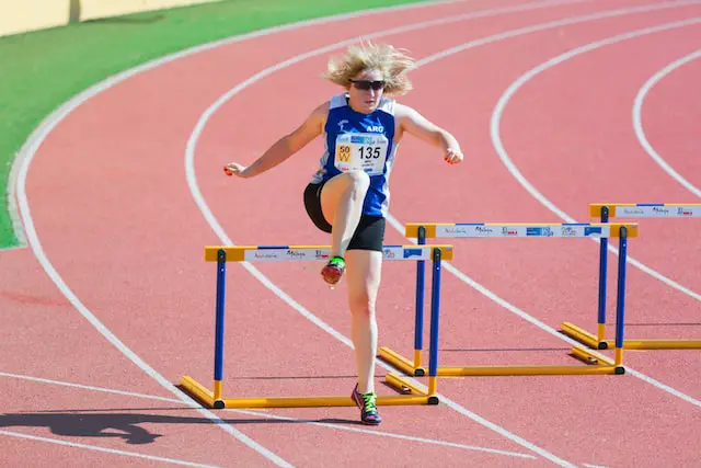 Picture of a woman athlete jumping a hurdle 