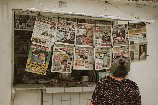 Woman looking at newspapers hanging from a wall