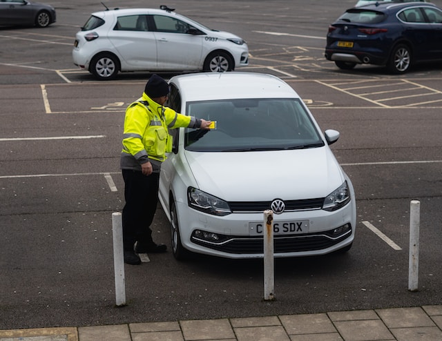 Picture of a policeman sticking a ticket on a car 