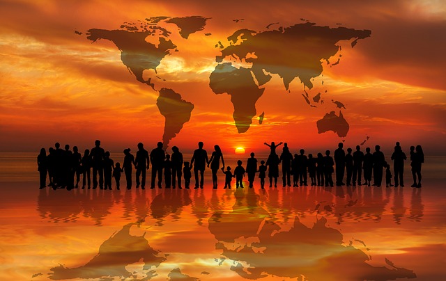 Picture of silhouettes of lots of people on the backdrop of a world map
