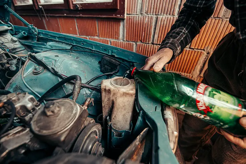 picture of a man poring antifreeze to his car engine