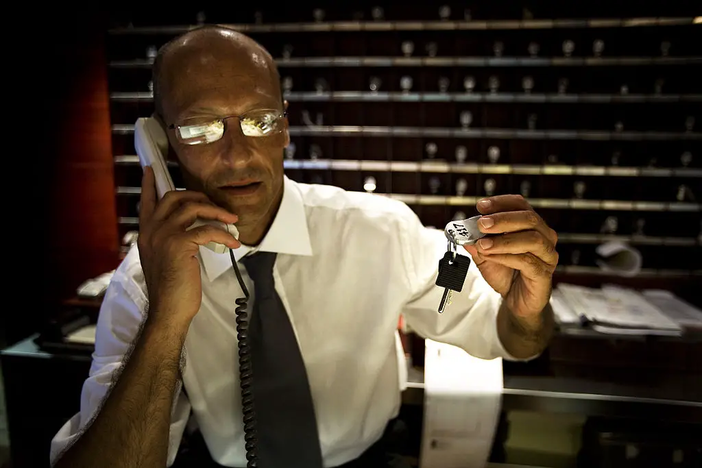 picture of a hotel concierge handing room keys and talking on the phone