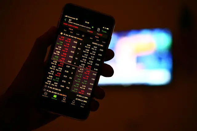 picture of a person with a mobile phone displaying stocks and shares 