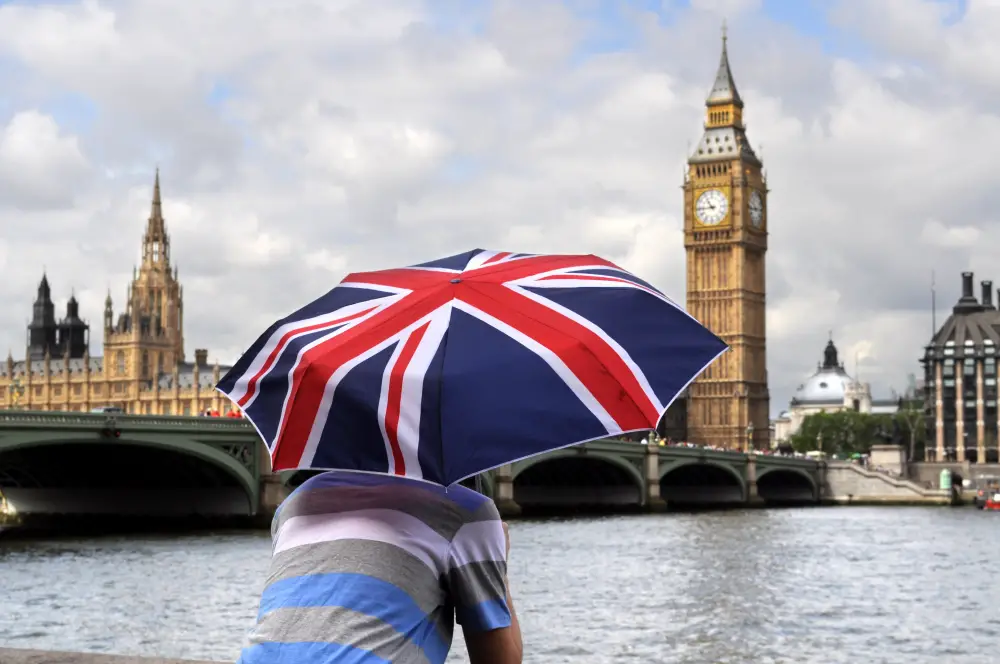 picture of a man looking at the big ben holding an union jack umbrella 